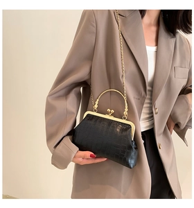Detail of vintage black crocodile embossed handbag with golden frame and pearl clasp