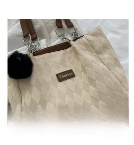 Detail of off-white quilted tote with brown leather straps and black pompom charm