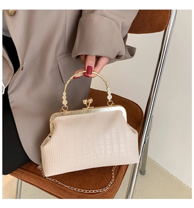 Detail of off-white crocodile embossed leather handbag with vintage kiss-lock and chain