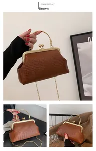 Detail of brown crocodile pattern handbag with gold floral handle and metal frame
