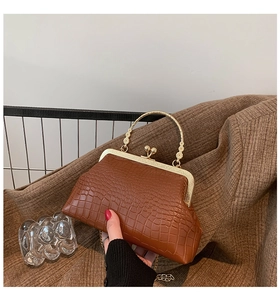 Detail of vintage brown crocodile embossed bag with gold kiss-lock and flower metal handle