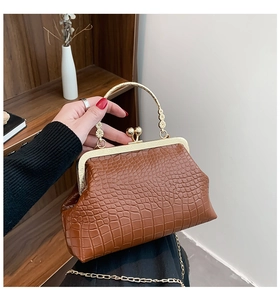 Detail of vintage brown crocodile embossed kiss-lock bag with floral gold handle