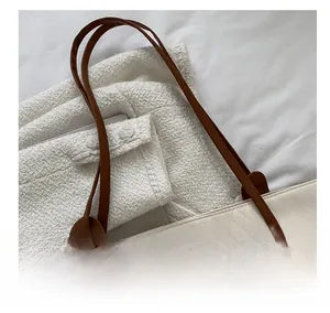 Detail of the white quilted tote bag showing brown leather handles and brand plaque