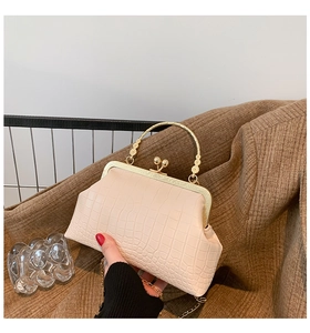 Close-up of cream crocodile pattern bag with vintage gold metal handle and chain strap