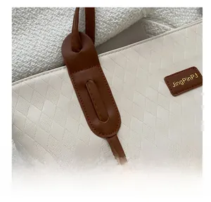 Close-up of white tote bag with quilted diamond pattern and brown leather straps