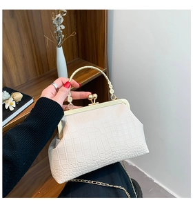 Detail of cream retro handbag with crocodile pattern and ornate golden floral handle
