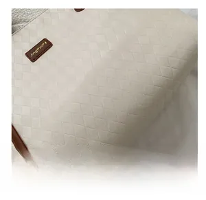 Close-up of beige quilted tote bag showing fine diamond patterns and leather logo tag