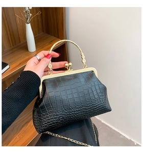 Close-up of black crocodile pattern frame bag with vintage gold clasp and carved handle
