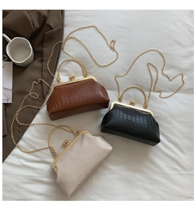 Detail view of retro crocodile pattern clutch bags with gold metal handles and chains