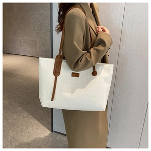 Detailed view of white quilted tote bag texture with brown leather straps on model