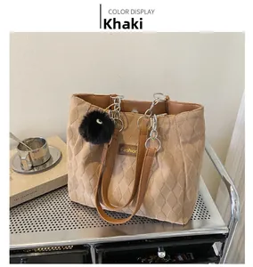 Detail of khaki quilted tote bag with brown straps and black faux fur pom-pom charm