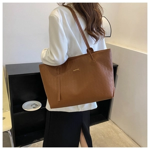 Detail of vintage brown tote bag with diamond lattice pattern and metal logo on a model