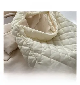 Detail showing quilted diamond stitching and soft puffy texture of off-white puffer bag