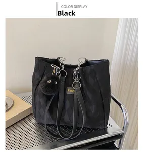 Detail of black quilted nylon tote bag with silver chain strap and furry ball charm