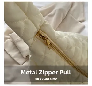 Detail of vintage gold metal zipper pull on cream quilted crossbody dumpling bag