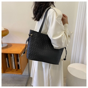 Close-up of black tote bag featuring geometric quilted texture and side drawstring detail