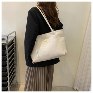 Minimalist white tote bag with woven texture worn by model in an office setting