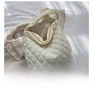 Close-up of a cream quilted shoulder bag showing large rhombic patterns and texture