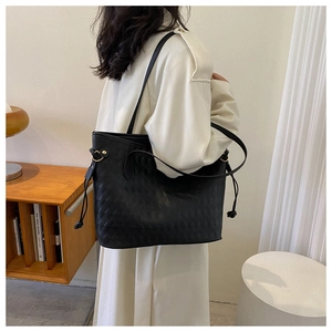 Detail of black tote bag featuring rhombus pattern and drawstring on white coat model