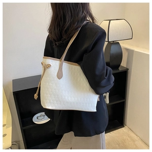Detail of white quilted tote bag with brown straps and side drawstring on model