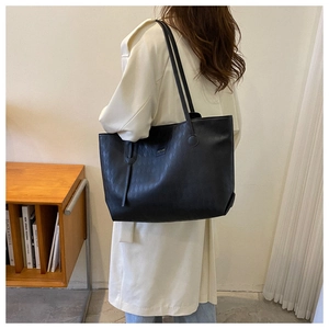 Side view of black quilted tote bag featuring elegant diamond lattice leather pattern