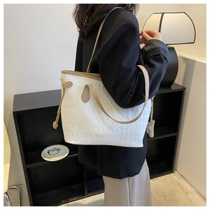 Close-up of white quilted tote bag with tan leather straps and side drawstring detail