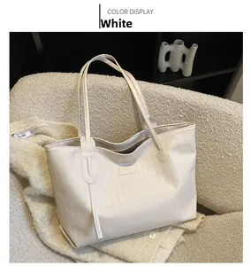 Detail of white quilted tote bag with long handles and tassel on knit background