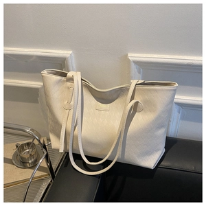 Detail of cream quilted tote bag featuring gold logo and fine PU leather texture