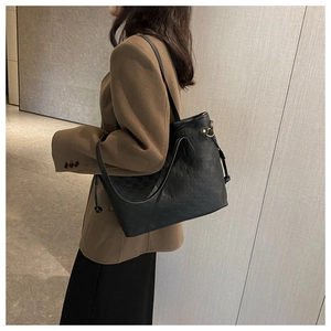 Detail of black tote bag featuring textured checkerboard pattern and drawstring side accents