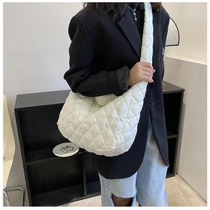 Detail of white quilted hobo bag with moon shape design and rhombus pattern texture