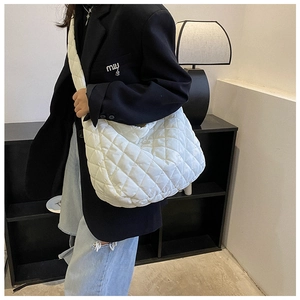 Detailed view of a white quilted hobo bag featuring plush puffy nylon fabric and wide strap