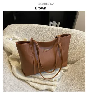 Detail of brown faux leather tote bag featuring quilted diamond pattern and metal logo