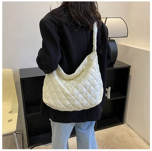 Model view of large cream quilted dumpling bag with wide shoulder strap and puff design