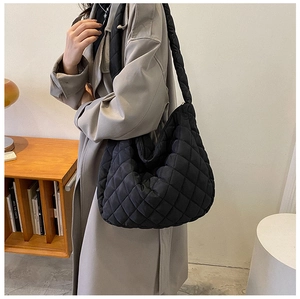 Detail of a black quilted hobo bag with sleek nylon finish on a female model