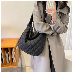 Detail of black quilted cloud tote bag with diamond stitching shown on shoulder