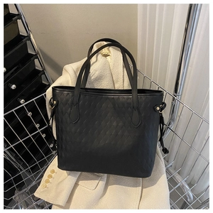 Detail of black quilted tote bag featuring a drawstring side and golden metal buckle