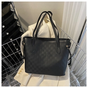 Detail of black tote bag with checkered embossing and gold metal rivets in a cart