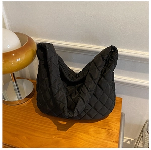 Close-up of black quilted cloud bag texture and nylon fabric on wooden surface