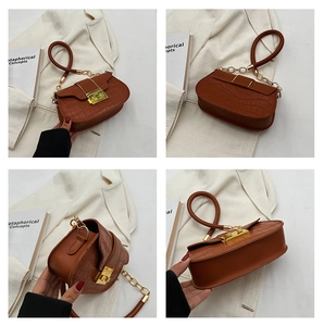 Detail view of brown crocodile embossed bag with gold chain and circular handle