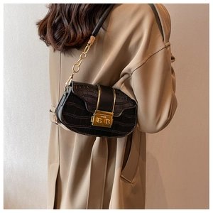 Detail of black faux crocodile leather crossbody bag with gold chain strap on model