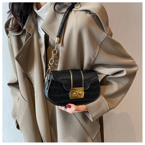 Detail of black faux crocodile skin shoulder bag with gold chain and metal buckle