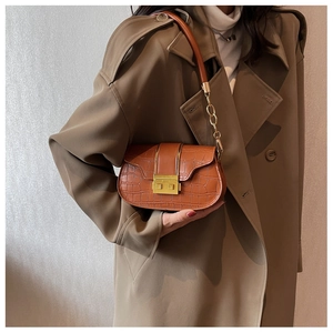 Brown faux crocodile leather underarm bag with gold buckle on trench coat outfit