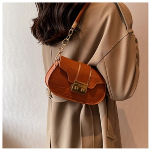 Detail of caramel crocodile pattern shoulder bag with gold metal lock and chain strap