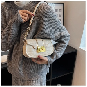 Detail of cream croc-embossed leather texture with gold square metal twist lock