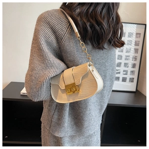 Detailed view of crocodile texture on cream shoulder bag with gold metal clasp
