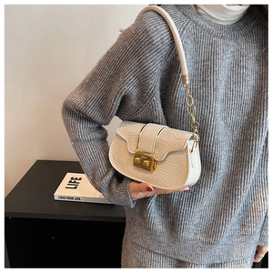 Detail of white crocodile pattern shoulder bag featuring golden metallic clasp and chain