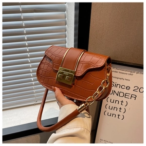 Detailed view of caramel brown crocodile embossed faux leather bag with gold chain strap