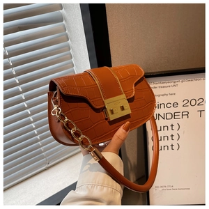 Close-up of caramel crocodile pattern shoulder bag with golden metallic clasp detail