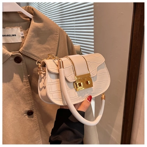 Detail of white crocodile pattern shoulder bag with a gold metal clasp and chain strap