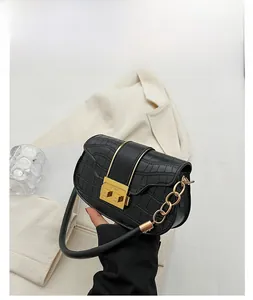 Detail of black faux leather crossbody bag featuring gold chain strap and stone texture